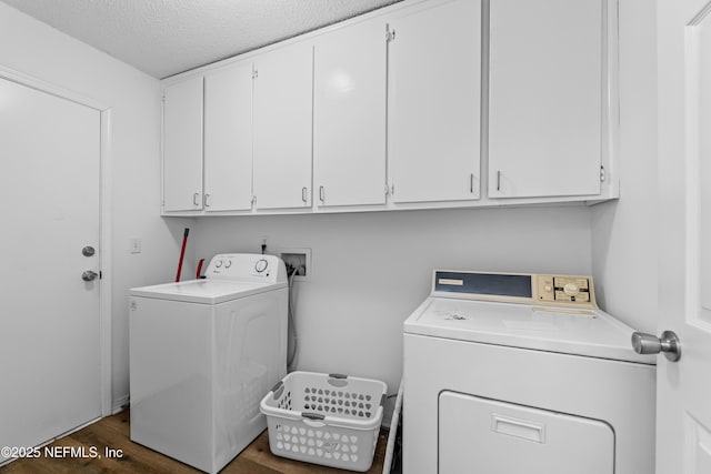 washroom featuring washer and dryer, a textured ceiling, dark wood-type flooring, and cabinet space