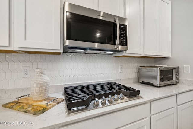 135 Neighbor Ct, Saint Augustine, FL 32092 - kitchen with decorative backsplash, light stone countertops, a toaster, stainless steel appliances, and white cabinetry