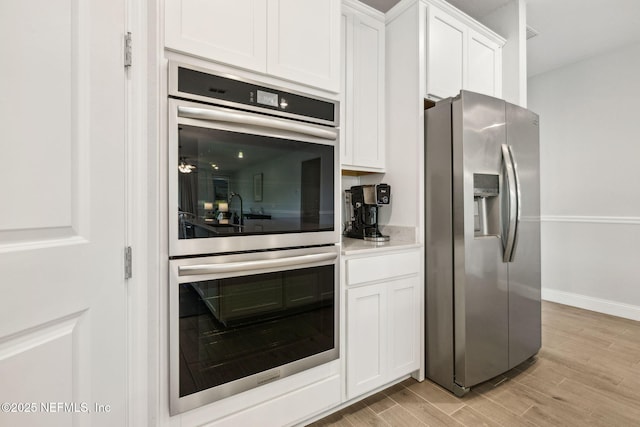 135 Neighbor Ct, Saint Augustine, FL 32092 - kitchen with white cabinets, light countertops, stainless steel appliances, baseboards, and light wood-type flooring