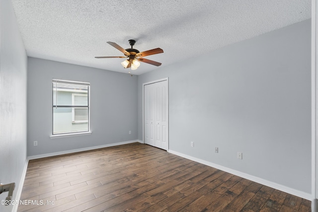 empty room with a textured ceiling, ceiling fan, baseboards, and dark wood-type flooring