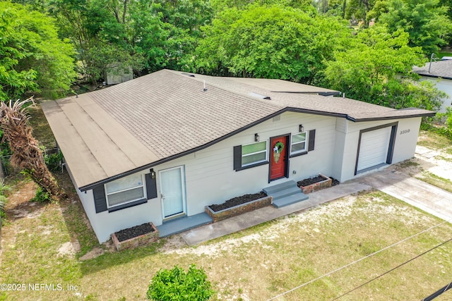 single story home with roof with shingles, concrete driveway, a front lawn, and a garage