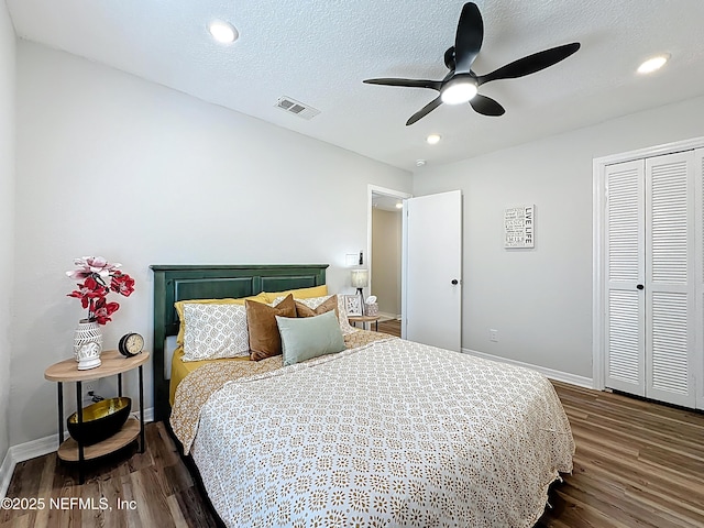 bedroom with visible vents, ceiling fan, a closet, baseboards, and dark wood-type flooring