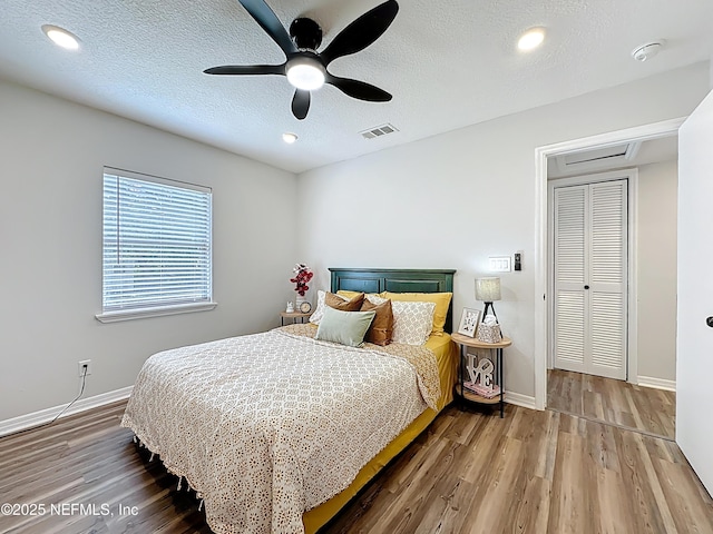 bedroom with a ceiling fan, visible vents, wood finished floors, and baseboards