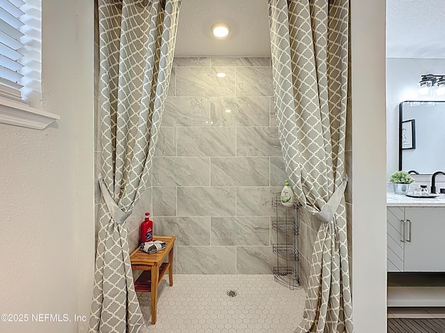 bathroom featuring a textured ceiling, a walk in shower, and vanity