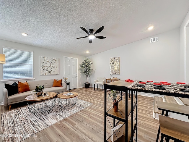 living room featuring ceiling fan, light wood-type flooring, and visible vents