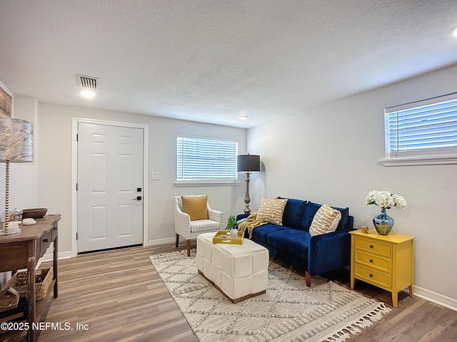 sitting room with a wealth of natural light, visible vents, light wood-type flooring, and baseboards