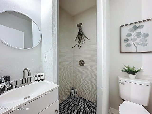 bathroom with vanity, toilet, and tiled shower