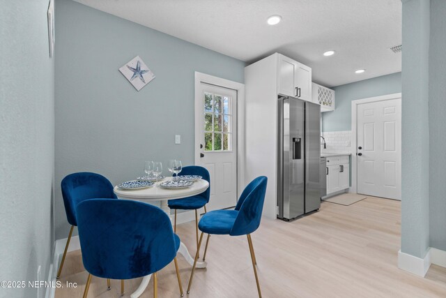 dining space with light wood-style floors, visible vents, and baseboards