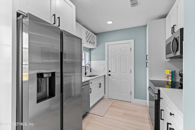 kitchen with white cabinetry, visible vents, stainless steel appliances, and a sink
