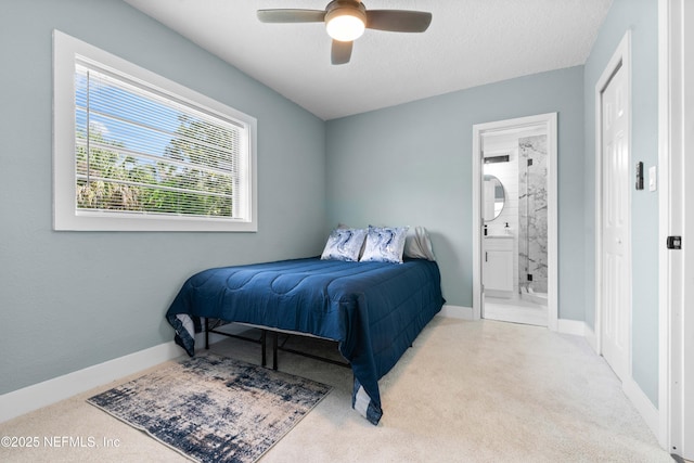 bedroom featuring a ceiling fan, baseboards, carpet floors, and ensuite bath