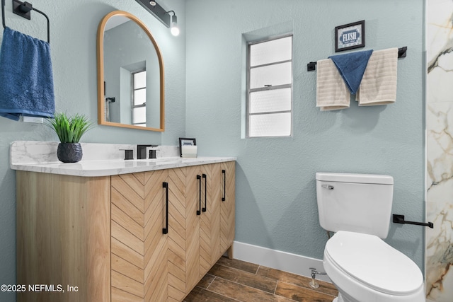 bathroom featuring wood tiled floor, vanity, toilet, and baseboards