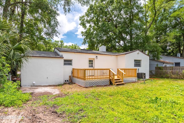 rear view of house featuring a chimney, stucco siding, fence, cooling unit, and a lawn