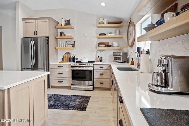 kitchen featuring open shelves, a sink, lofted ceiling, and stainless steel appliances