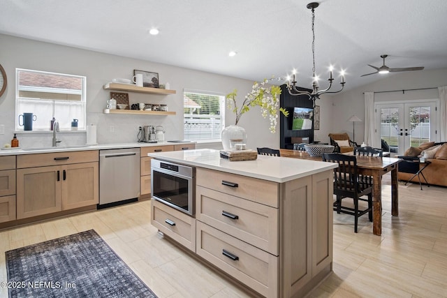 kitchen featuring a sink, light countertops, french doors, open floor plan, and stainless steel dishwasher
