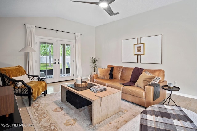 living area with light wood finished floors, french doors, a ceiling fan, baseboards, and lofted ceiling