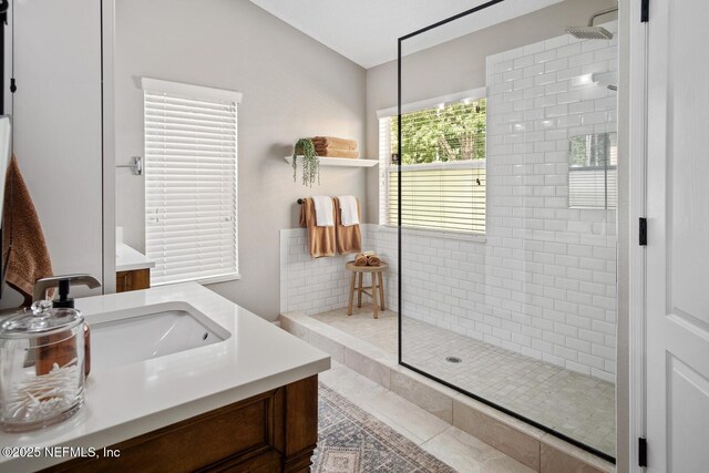 bathroom with a tile shower and vanity