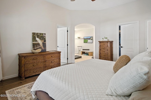 bedroom featuring baseboards, a ceiling fan, arched walkways, and wood finished floors