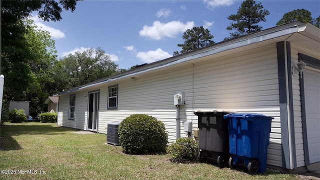 view of property exterior with a yard, central AC unit, and a garage