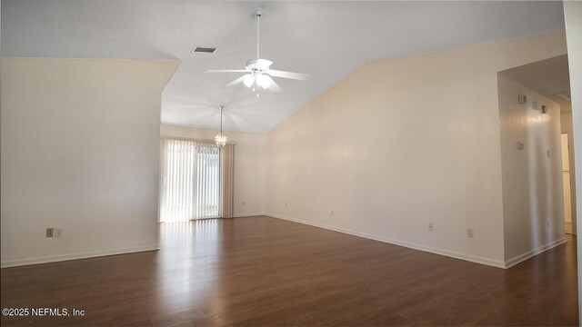 spare room featuring visible vents, dark wood-style floors, vaulted ceiling, and ceiling fan with notable chandelier