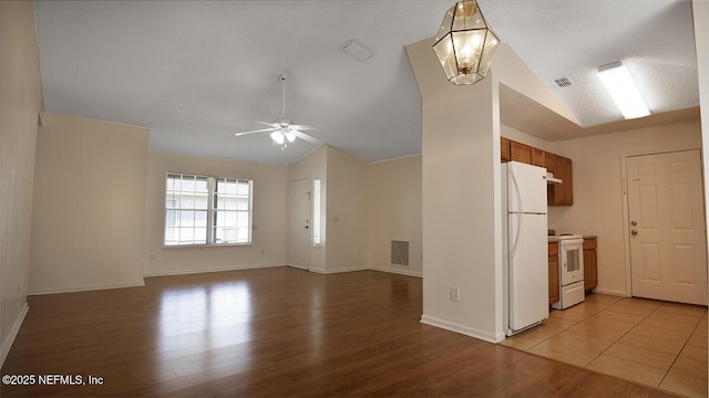 kitchen with light wood finished floors, a ceiling fan, visible vents, white appliances, and lofted ceiling