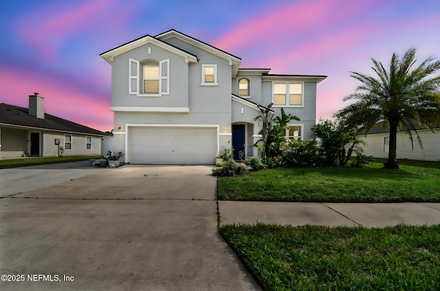 traditional home with stucco siding, concrete driveway, a lawn, and a garage