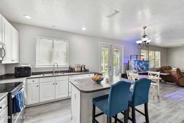 kitchen featuring visible vents, white dishwasher, stainless steel electric range, a sink, and light wood-type flooring