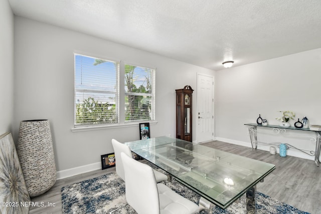 dining space featuring a textured ceiling, wood finished floors, and baseboards