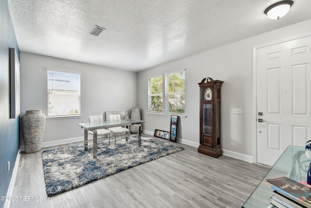 office area with baseboards, visible vents, wood finished floors, and a textured ceiling