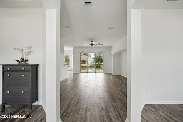 interior space featuring arched walkways, visible vents, baseboards, and dark wood-type flooring