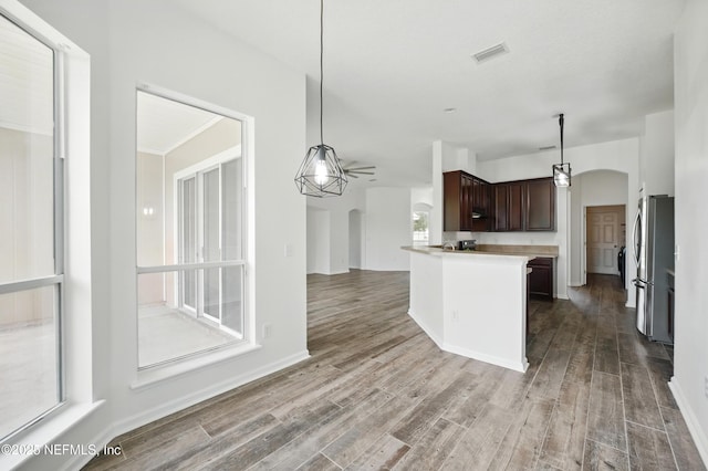 kitchen with dark brown cabinetry, a ceiling fan, visible vents, arched walkways, and freestanding refrigerator