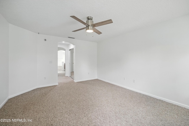 unfurnished room featuring ceiling fan, visible vents, light carpet, baseboards, and arched walkways