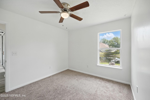 carpeted empty room featuring ceiling fan and baseboards