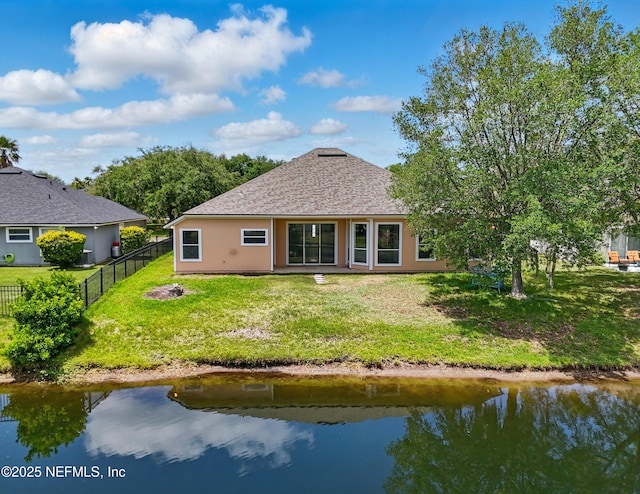 back of house with fence, a yard, a shingled roof, and stucco siding