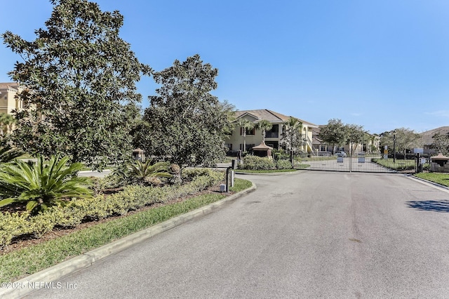 view of street featuring a gate, a residential view, curbs, and a gated entry