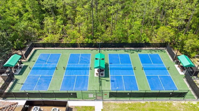 view of sport court featuring fence and a view of trees