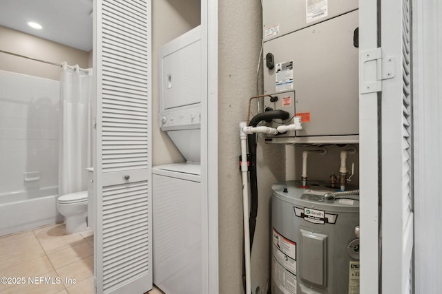 laundry room featuring stacked washing maching and dryer, laundry area, light tile patterned flooring, and electric water heater