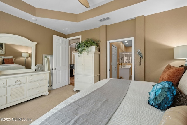 bedroom featuring visible vents, light colored carpet, and ensuite bathroom