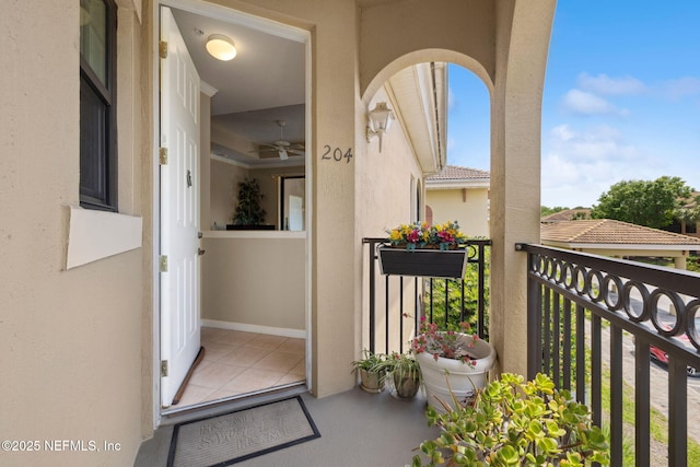 doorway to property with stucco siding, ceiling fan, and a balcony