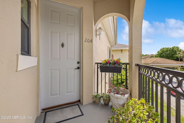 doorway to property featuring stucco siding and a balcony
