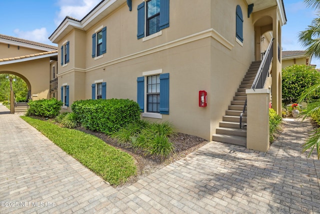 view of side of property featuring stairway and stucco siding