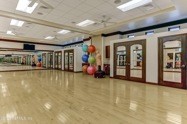 workout room with wood finished floors, french doors, and a paneled ceiling
