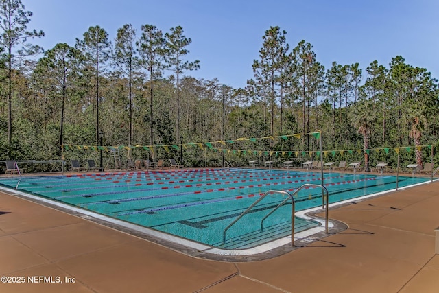 community pool with a wooded view and fence