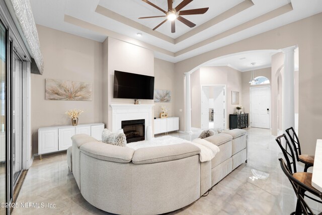 1071 Green Pine Cir, Orange Park, FL 32065 - living room featuring a ceiling fan, a tray ceiling, decorative columns, a fireplace, and arched walkways