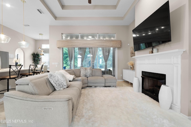 1071 Green Pine Cir, Orange Park, FL 32065 - living area featuring a fireplace, a tray ceiling, arched walkways, baseboards, and ceiling fan