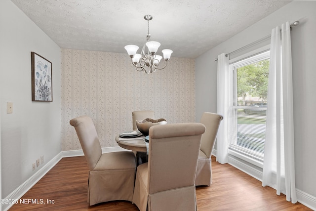 dining space featuring an inviting chandelier, wood finished floors, and baseboards