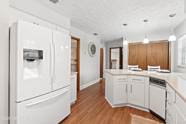 kitchen with white fridge with ice dispenser, a peninsula, light wood-style flooring, and a textured ceiling