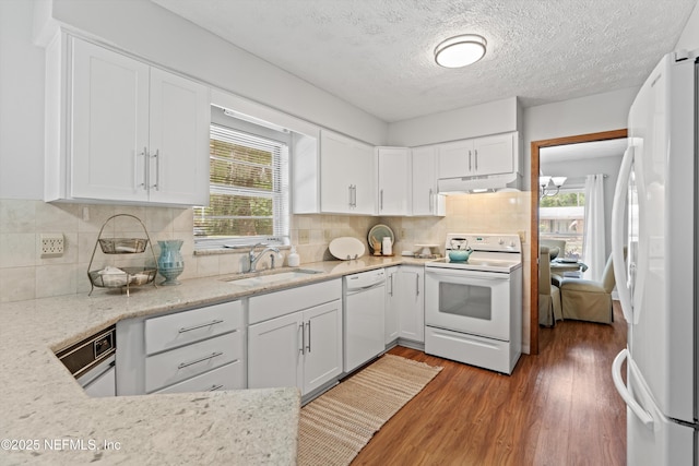 kitchen with a sink, white cabinets, wood finished floors, and white appliances