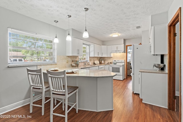 kitchen with white appliances, a textured ceiling, white cabinetry, light wood-type flooring, and a peninsula