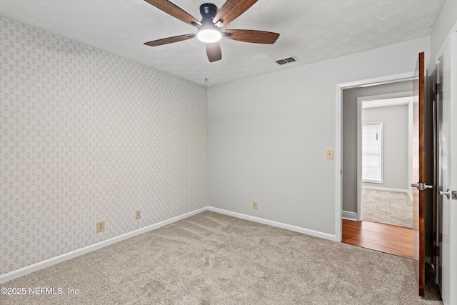unfurnished bedroom with carpet, visible vents, wallpapered walls, and baseboards