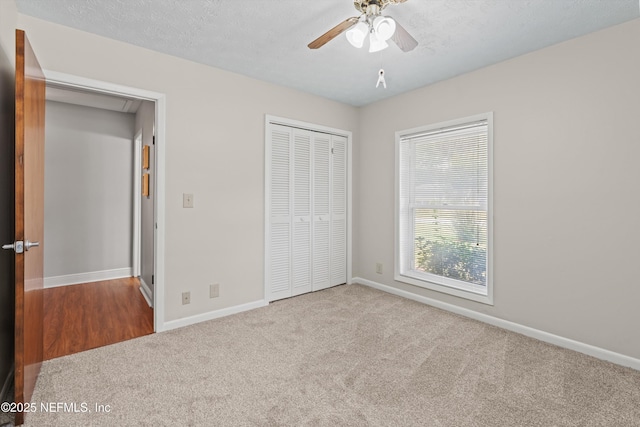 unfurnished bedroom featuring ceiling fan, a closet, carpet flooring, and baseboards